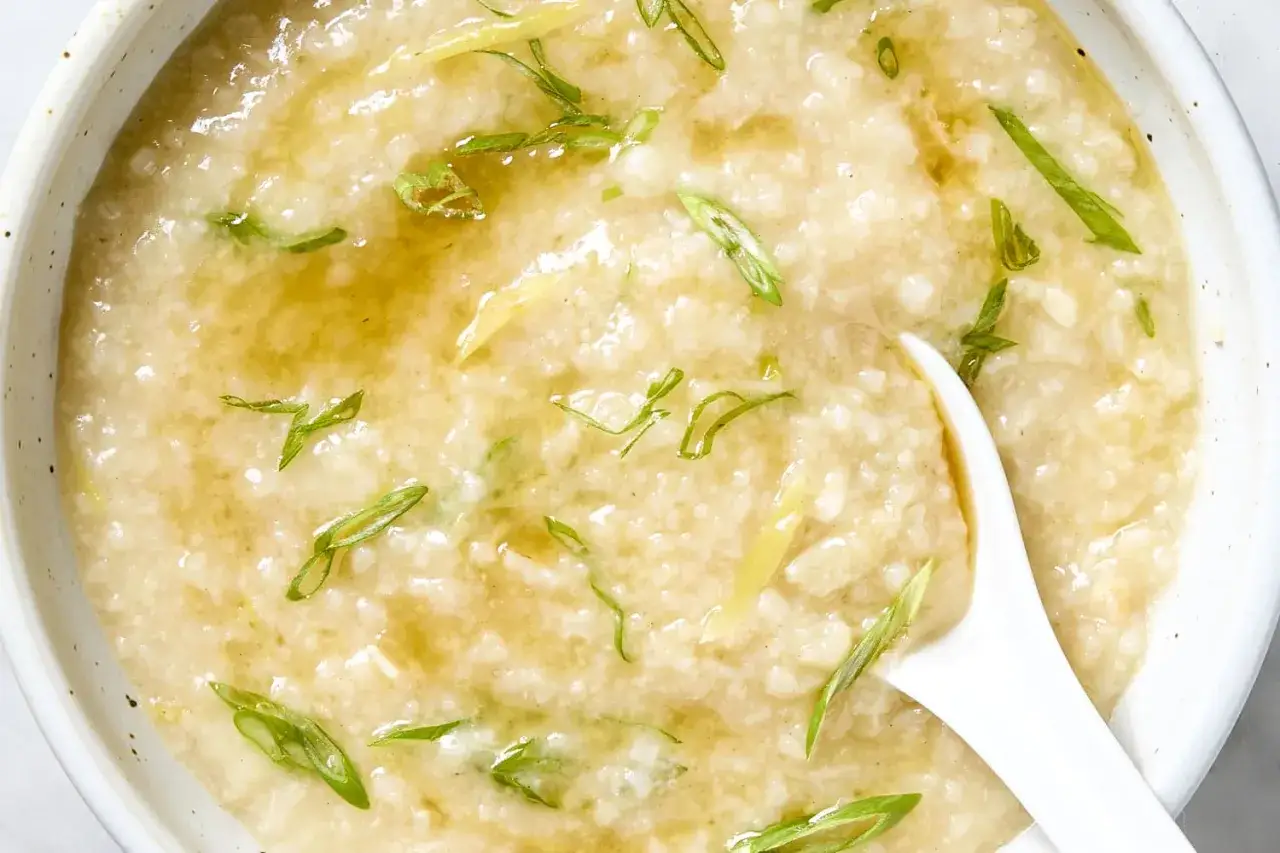 Gęste, kremowe congee z ryżu, ozdobione szczypiorkiem i imbirem, gotowe do spożycia.