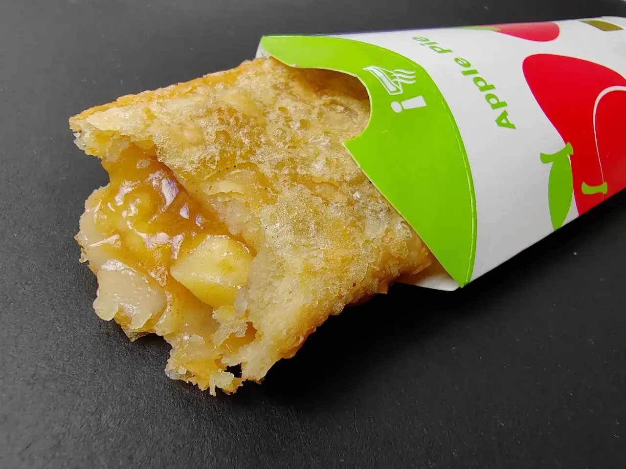 Częściowo zjedzone ciastko jabłkowe z McDonald's, w papierowym opakowaniu z napisem 