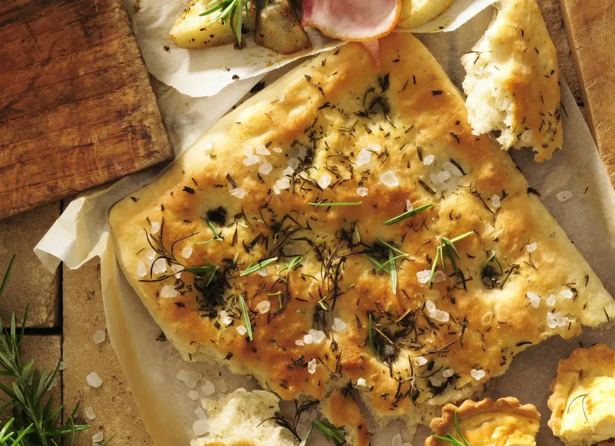 Oryginalna włoska focaccia przepis: złocista, chrupiąca, z rozmarynem i solą morską, obok pieczone ziemniaki i mini tarty.