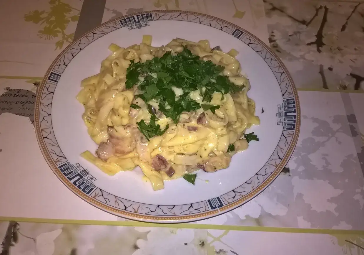 Pyszne spaghetti carbonara, przepis oryginalny ze śmietaną, z kawałkami boczku i posypane świeżą natką pietruszki.