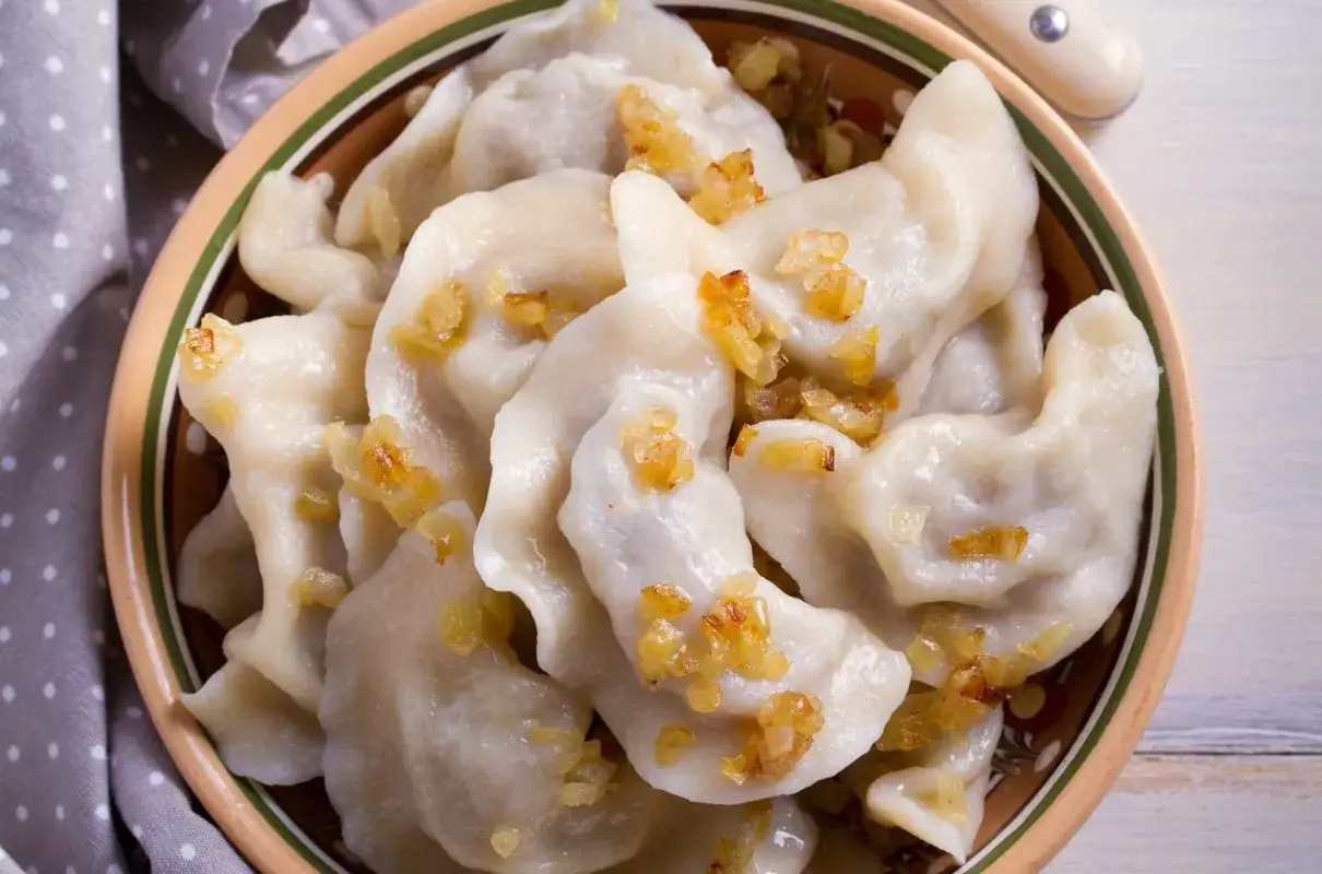 Pyszne pierogi chłopskie, okraszone skwarkami, w glinianej misie.