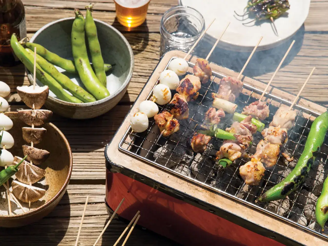 Grillowane yakitori z kurczakiem i jajkami przepiórczymi, obok miska fasolki i pieczarki na patyczkach.