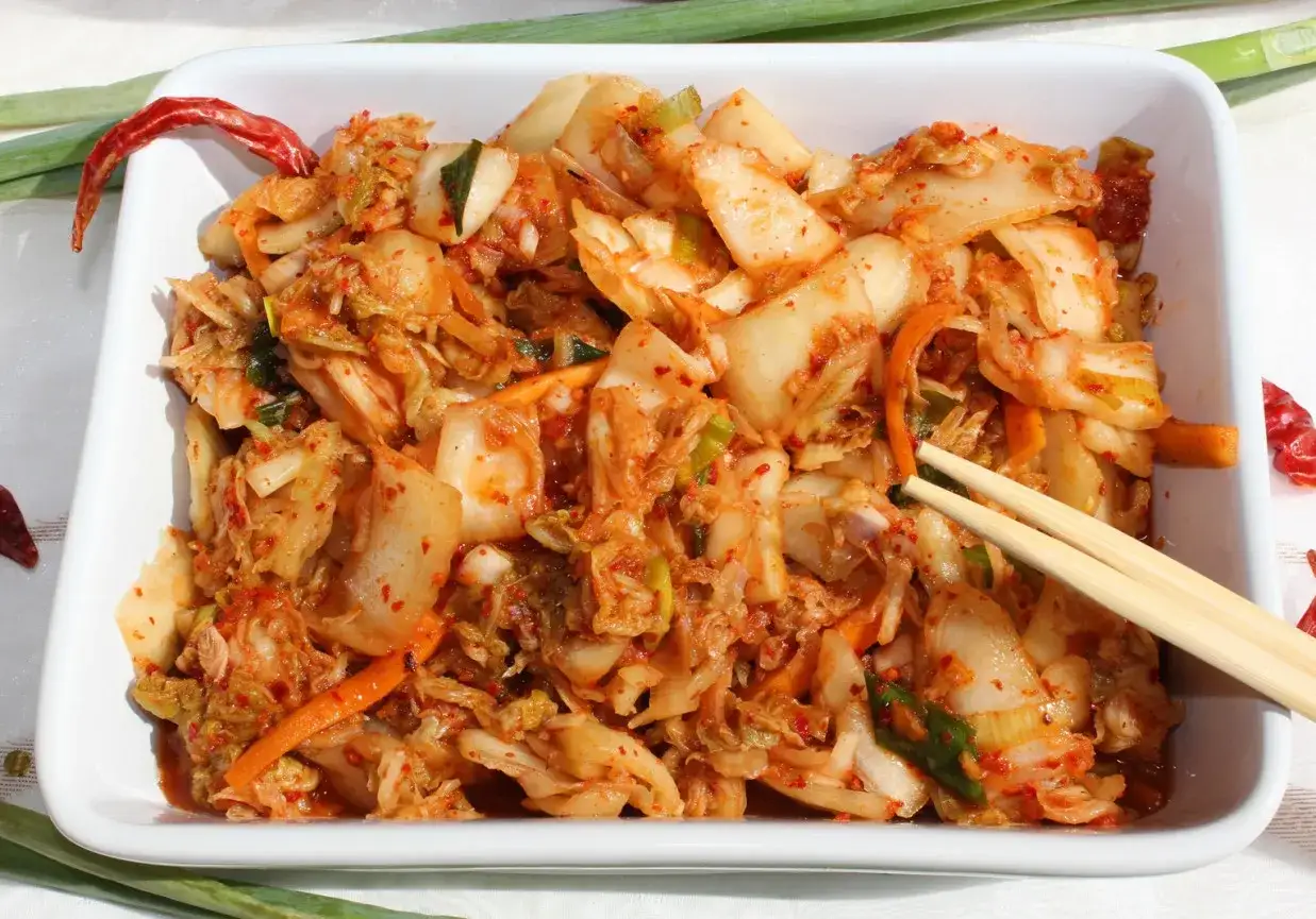Pikantne, fermentowane warzywa, czyli kimchi. Widok na miskę pełną tej koreańskiej potrawy, z pałeczkami do jedzenia.
