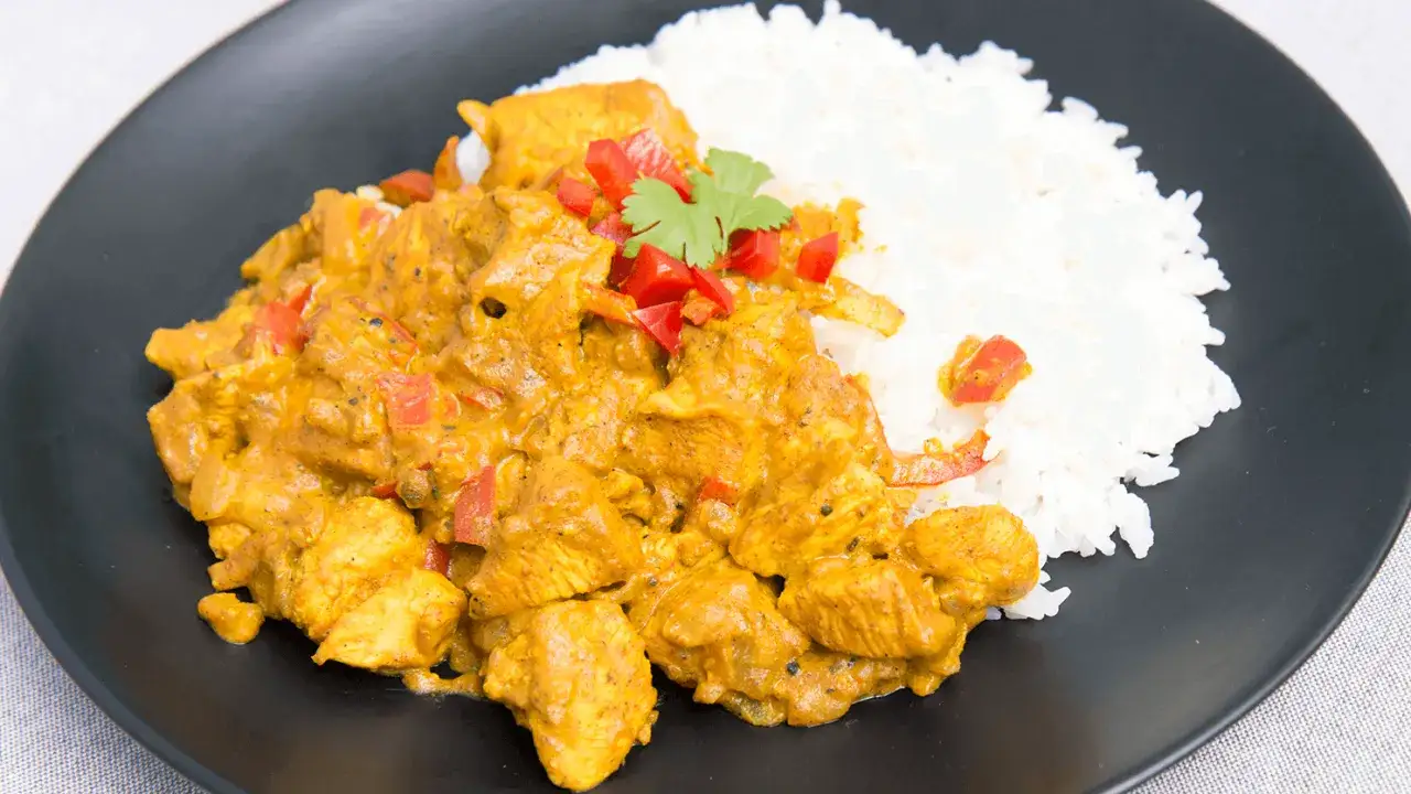 Kurczak w sosie curry z ryżem, posypany papryką i kolendrą. Prosty przepis na pyszny obiad.