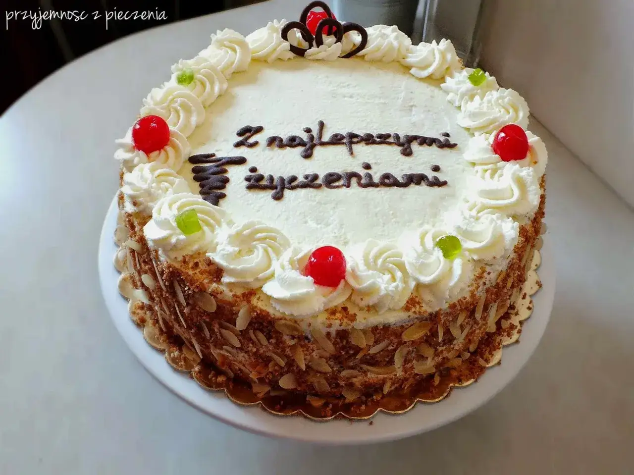 Tort z bitą śmietaną z mascarpone, ozdobiony wiśniami i żelkami, z napisem