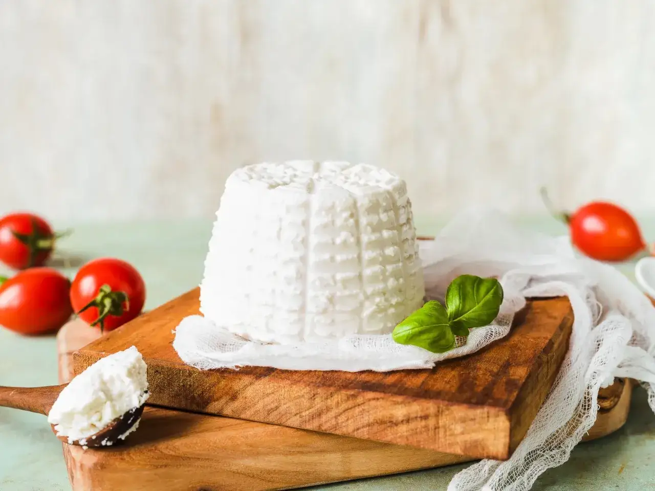 Świeży serek ricotta na desce z pomidorkami i bazylią. Idealny do letnich sałatek.