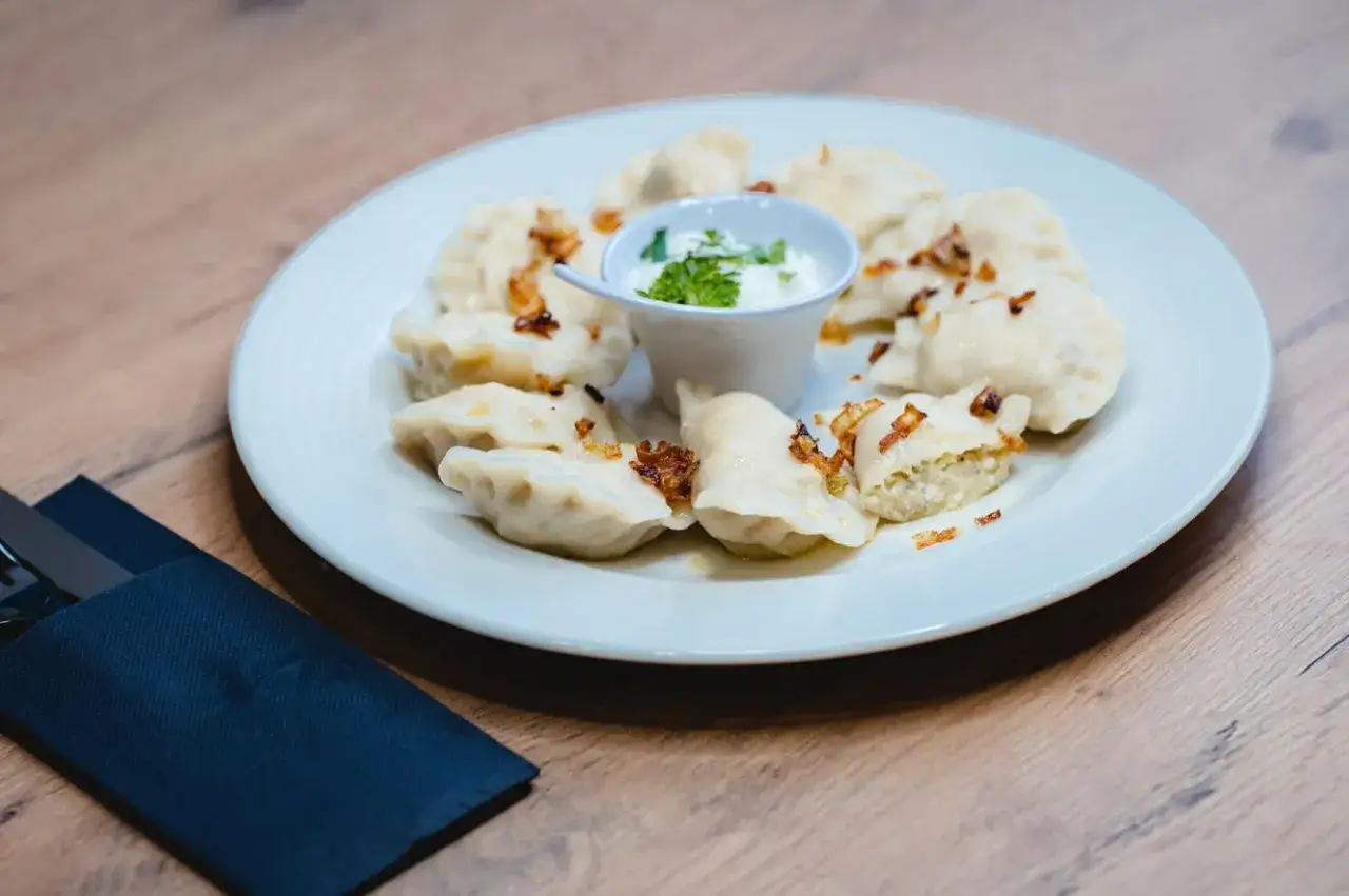 Pyszne pierogi ukraińskie z chrupiącą cebulką i śmietaną, gotowe do zjedzenia.