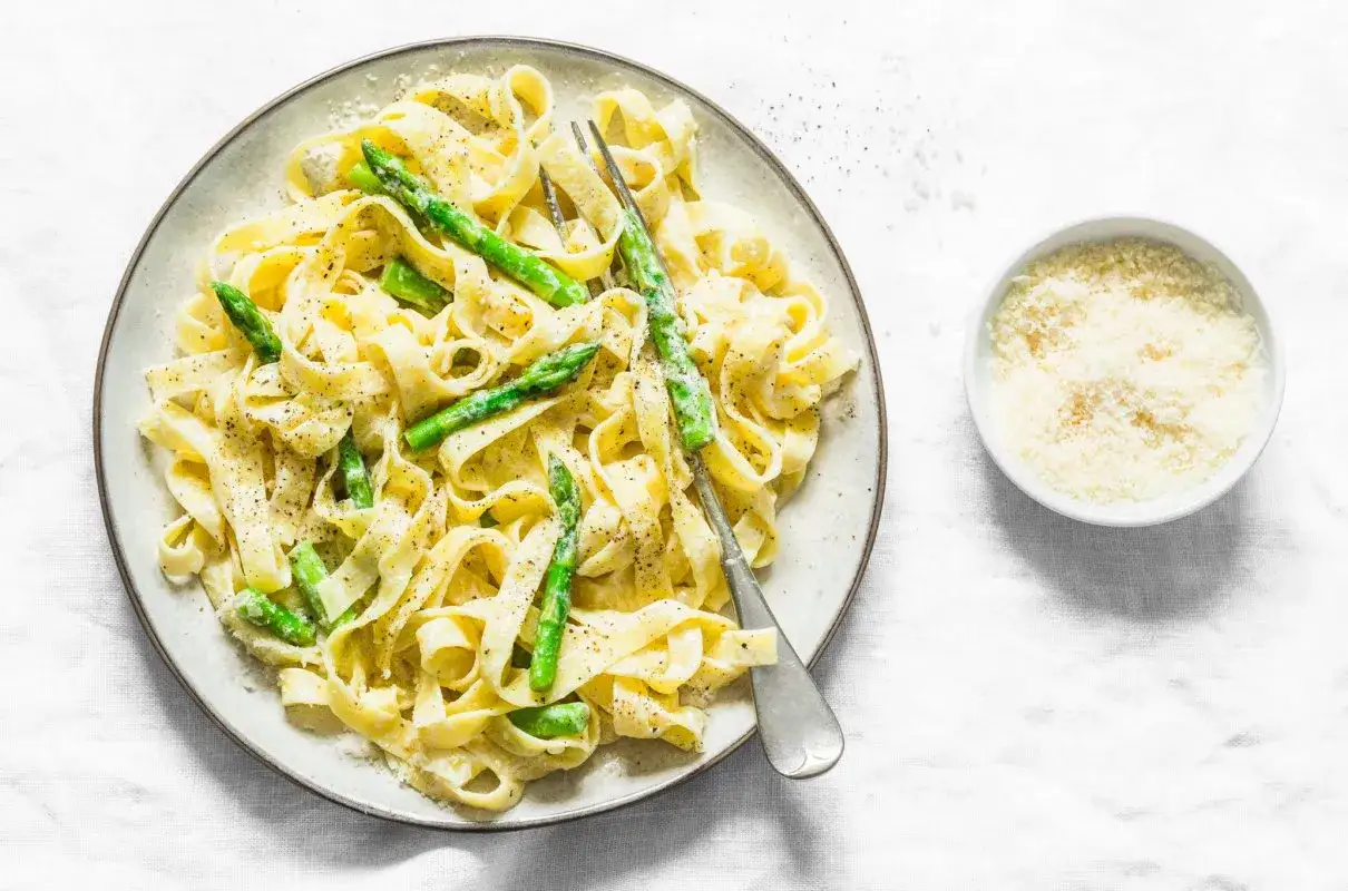 Tagliatelle ze szparagami w kremowym sosie, posypane parmezanem. Pyszne danie, które zachwyci każdego smakosza.