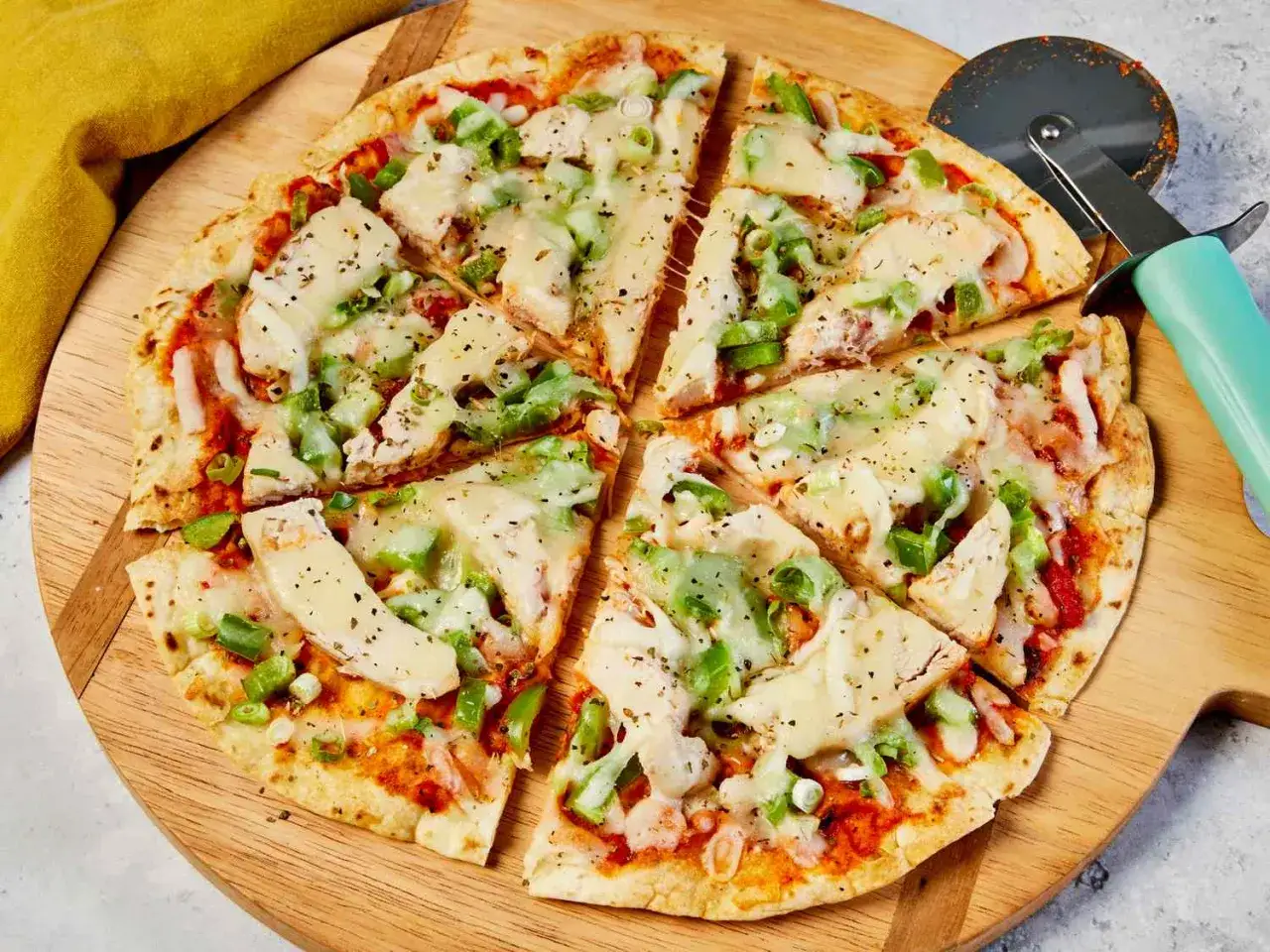 Szybka pizza z tortilli na patelni z kurczakiem i papryką, pokrojona na kawałki, gotowa do podania.