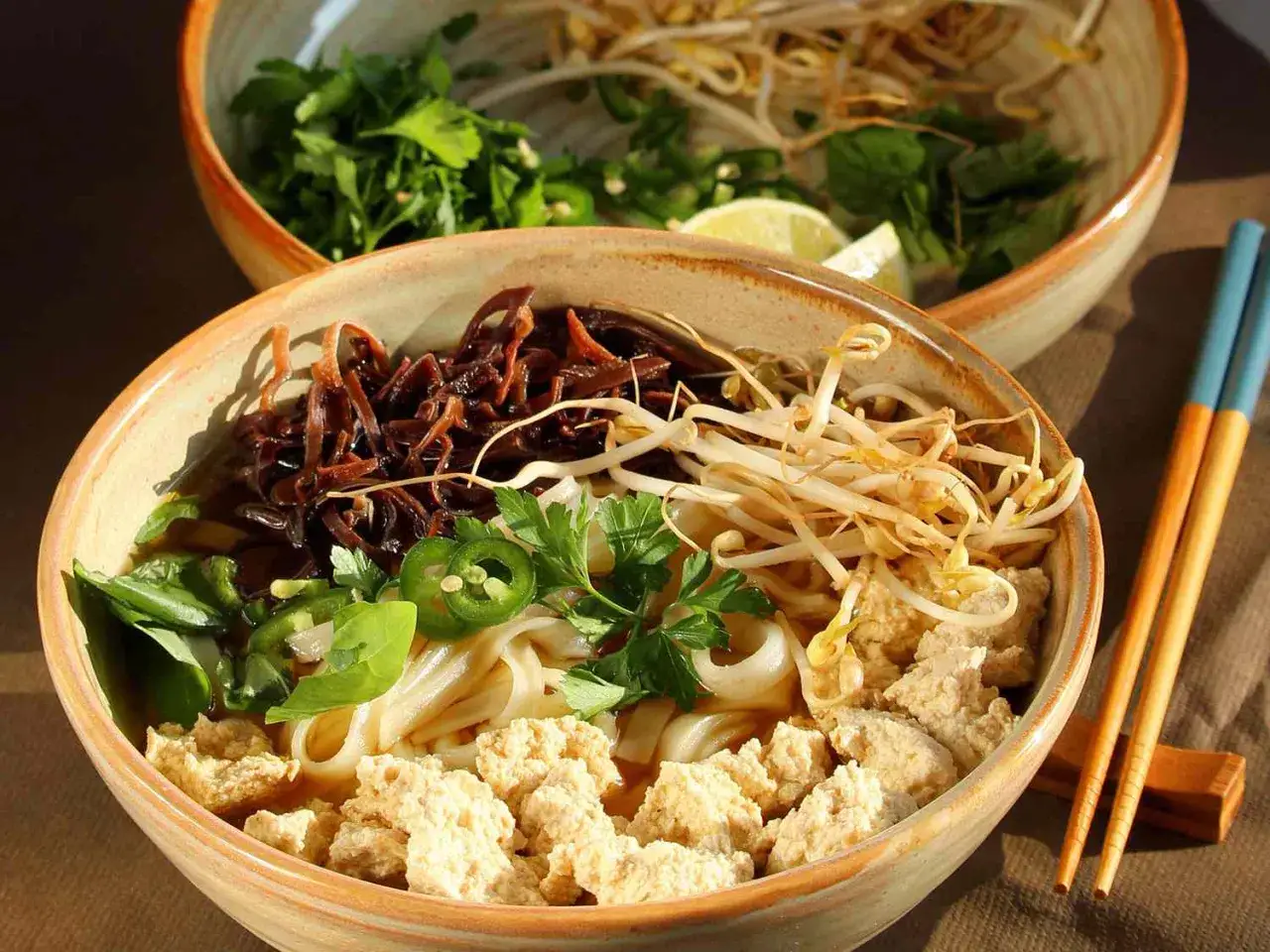 A miseczka aromatycznego pho z tofu, kiełkami, grzybami mun i świeżą kolendrą. Obok pałeczki.