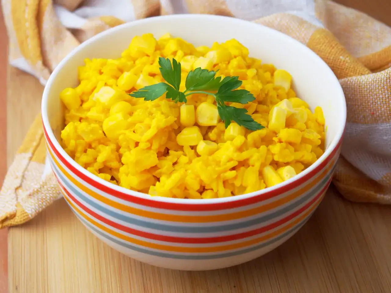 Miseczka kolorowego ryżu z curry i kukurydzą, ozdobiona natką pietruszki. Idealny na szybki obiad.