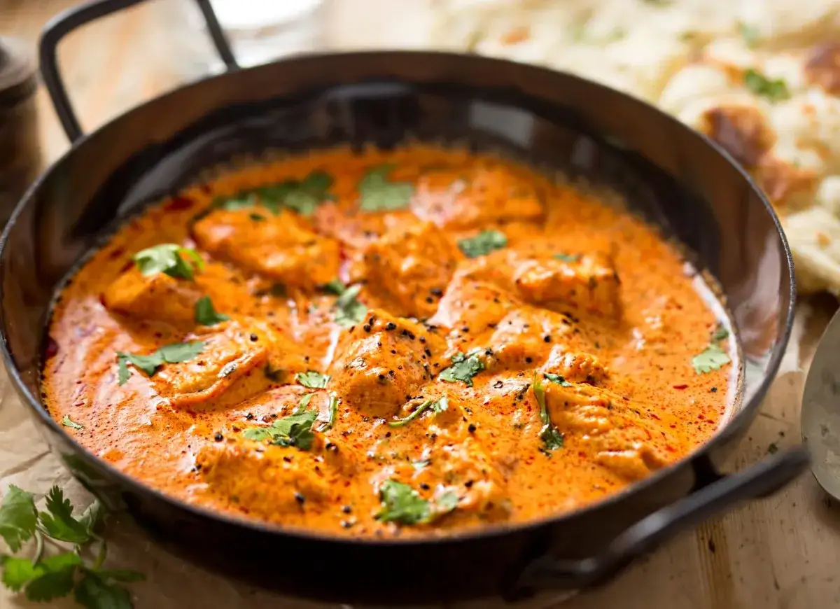 Aksamitny kurczak w sosie curry, idealny na prosty obiad. Aromatyczne kawałki kurczaka w kremowym, pomarańczowym sosie, posypane świeżą kolendrą.