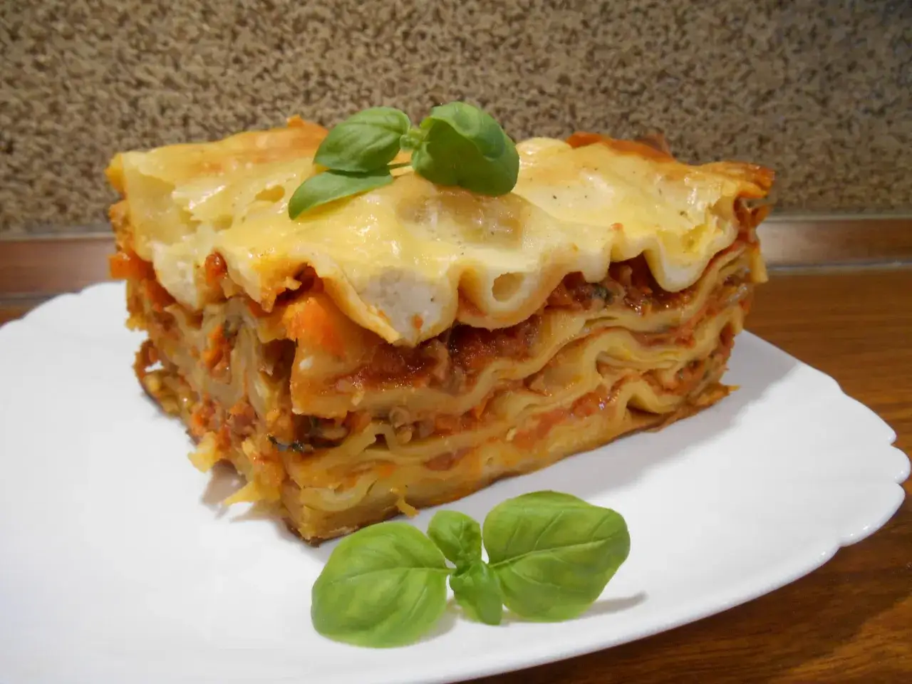 Pyszna, warstwowa lasagne z mięsem mielonym, udekorowana listkami bazylii. Idealna na prosty obiad.