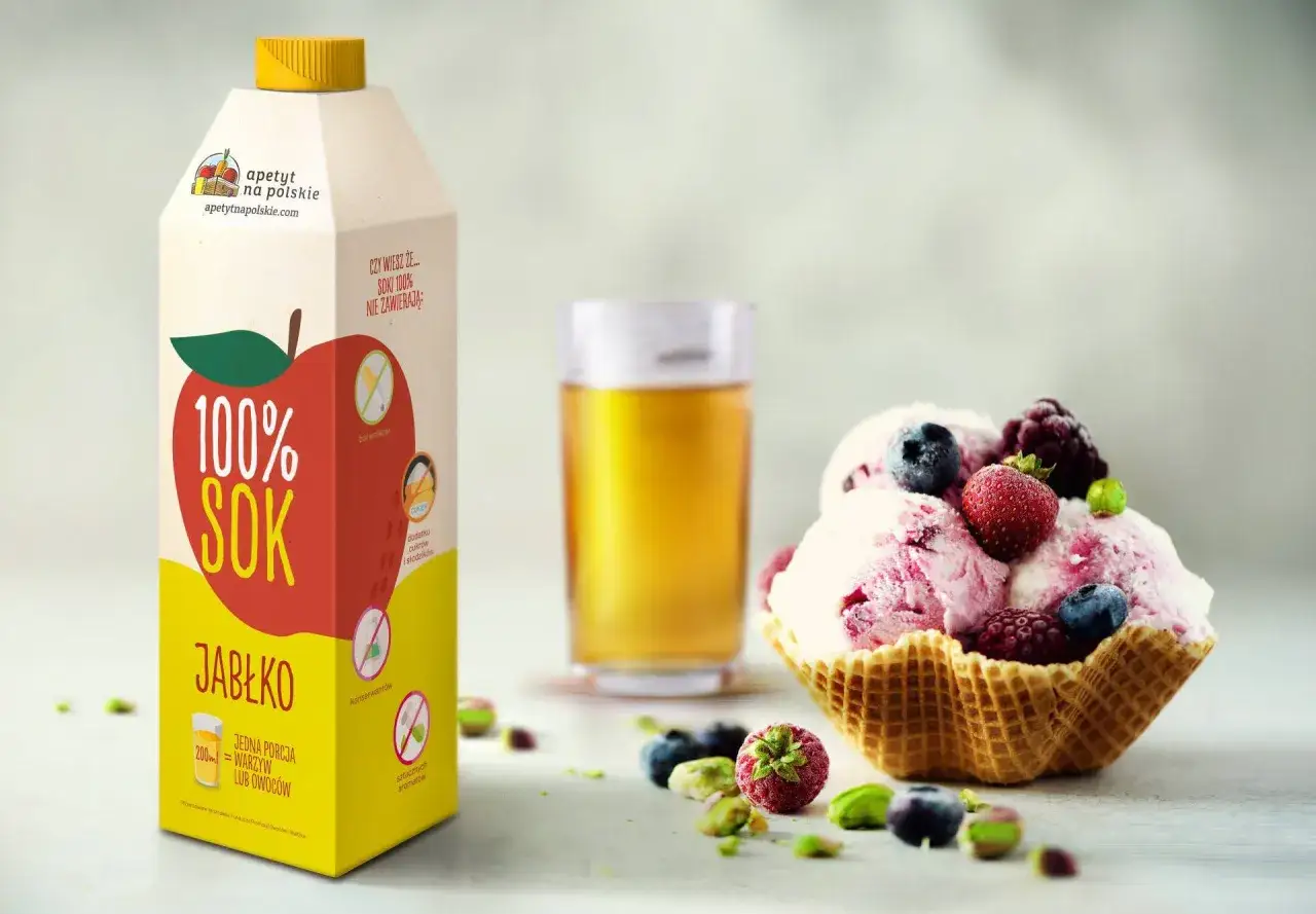 Pyszne domowe lody z owocami w wafelku, obok karton soku jabłkowego.