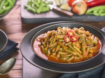 Fasolka szparagowa w sosie pomidorowym z plasterkami chili na wierzchu.