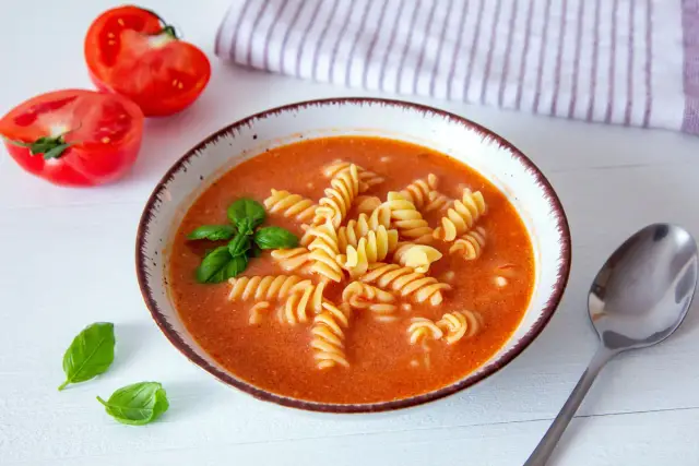 Miseczka zupy pomidorowej z makaronem fusilli, pomidorami i bazylią.