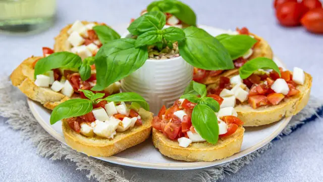 Bruschetta z pomidorami i mozzarellą, świeża bazylia i chrupiące pieczywo. Idealny przepis na letnią przekąskę.